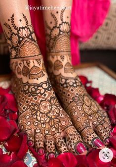 the feet and hands of a woman with henna tattoos on their legs, surrounded by red flowers