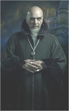 an old man with a long white beard wearing a black robe and holding his hands together