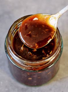 a spoon full of peanut butter on top of a glass jar filled with chocolate sauce