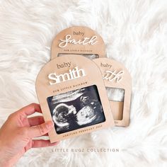 someone holding up two baby pictures in front of a white furnishing area with the words, baby smith on it