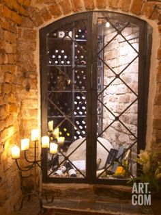 a wine cellar with candles and bottles on the wall next to an open door that leads to another room