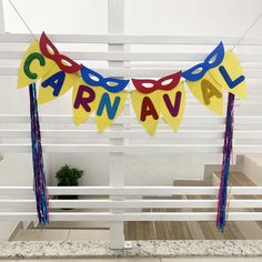 a carnival sign hanging from the side of a white building with blue and yellow streamers