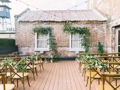 rows of wooden chairs sitting on top of a wooden floor next to a brick building