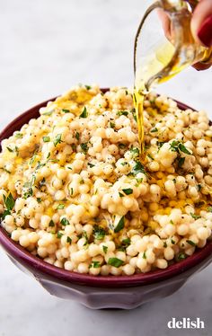 a bowl filled with macaroni and cheese being drizzled with dressing