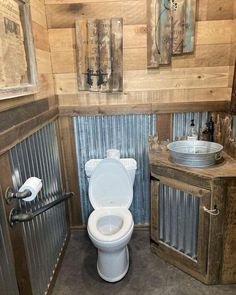 a white toilet sitting inside of a bathroom next to a wooden sink and counter top