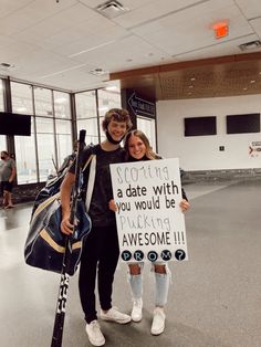 two people standing in an airport holding up a sign that says, sporting is a date with you would be pucking awesomely