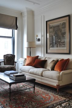 a living room filled with furniture and a painting hanging on the wall above it's windows