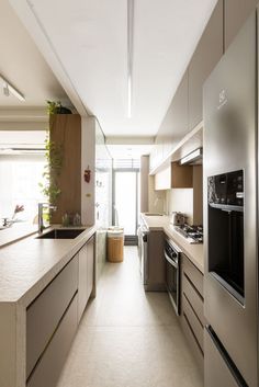 a long kitchen with stainless steel appliances and white counter tops, along with an open floor plan