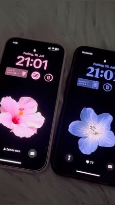 two cell phones displaying different time zones on their screens, one is pink and the other is blue