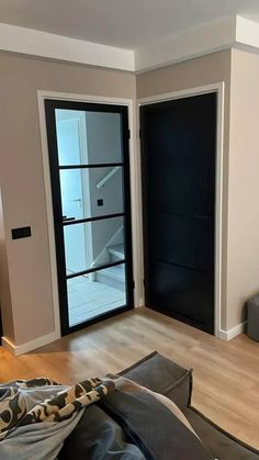 an empty living room with black doors and wood floors