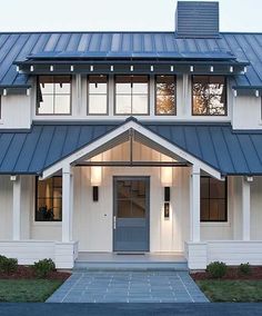 a white house with a blue roof and two story entryway leading to the front door