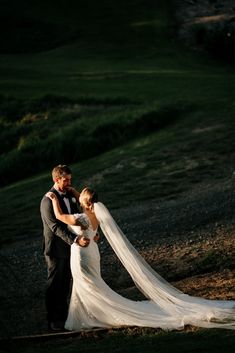 a bride and groom standing together in the sun at their outdoor wedding ceremony on a hillside