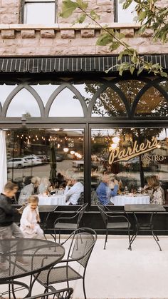 people sitting at tables in front of a restaurant with glass doors that read parker's