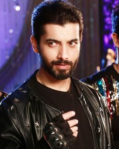 a man with a beard wearing a black shirt and holding his hand up to the camera