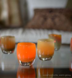 three orange candles sitting on top of a glass table