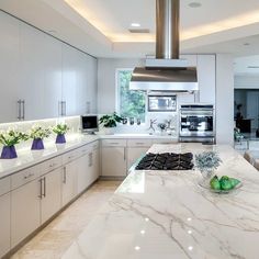 a large kitchen with marble counter tops and white cabinets, along with stainless steel appliances