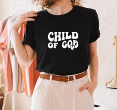 a woman wearing a black shirt that says child of god