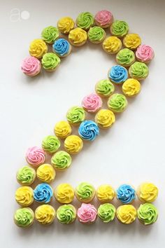 the number seven made out of cupcakes is decorated with multicolored icing