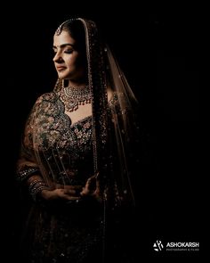 a woman in a bridal gown and veil poses for the camera with her hands on her hips