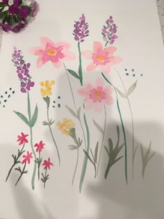 flowers are painted on a white paper with purple and yellow flowers in the background,