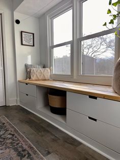 a window seat with storage drawers in front of it and a rug on the floor