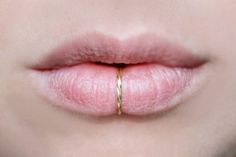 a woman's lips with a gold ring on her lip and the tip of her nose