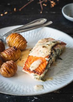 a white plate topped with meat covered in gravy next to croissants