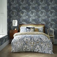 a bedroom with blue wallpaper and a bed in the middle, next to a window