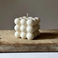 a white candle sitting on top of a wooden block