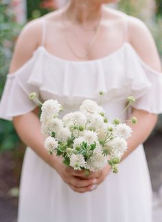 a woman in a white dress holding a bouquet of flowers