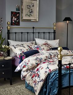 a bed with floral comforter and pillows in a bedroom next to a night stand