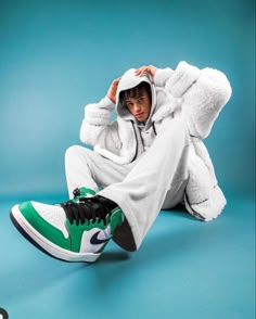 a man sitting on the ground wearing a white and green sneaker