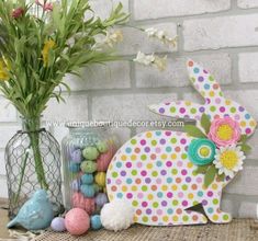 a wooden bunny sitting next to some flowers