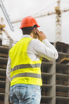 a construction worker talking on his cell phone in front of a building under construction royalty images