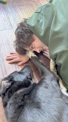 a person laying on the floor with a dog sleeping next to them and covering their face