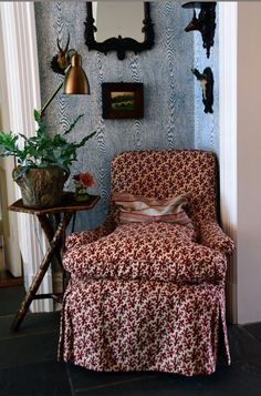 a living room with a chair, mirror and vase on the wall next to it