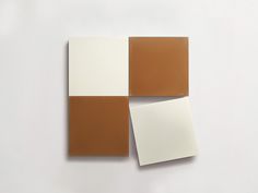 three pieces of white, brown and beige tile on a white surface with one piece missing