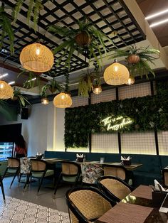 an indoor restaurant with plants hanging from the ceiling and tables set up in front of them