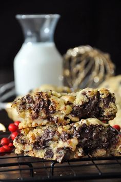 two chocolate chip cookies stacked on top of each other next to berries and a glass of milk