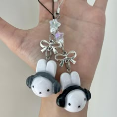 two white and black rabbit shaped keychains hanging from a person's hand