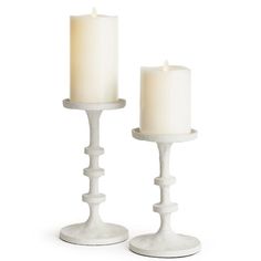 two white candles sitting next to each other