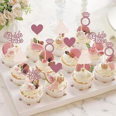 cupcakes decorated with pink and white frosting are on a tray next to flowers