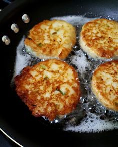 four pieces of fried food cooking in a frying pan with oil on the side