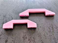 two pink plastic objects sitting on top of a wet surface