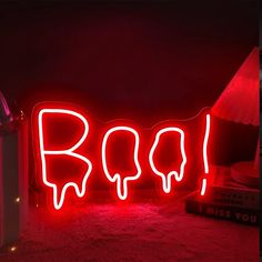 a red neon sign that says boo on the floor next to a trash can and lamp