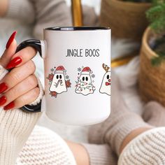 a woman holding a coffee mug with two ghost faces on it and the words jungle boos