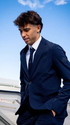 a man in a suit and tie standing next to an airplane with his hands on his hips