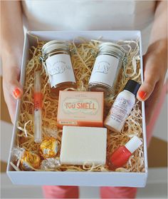 a person holding a box with some items in it that include soap, lip balm, and lotion