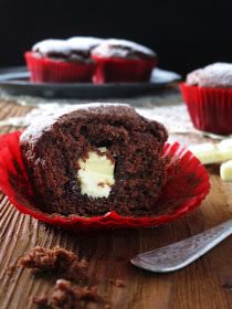 a chocolate muffin with white frosting on a wooden table