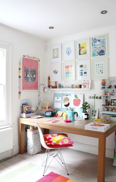 a desk with pictures on the wall above it and a chair in front of it